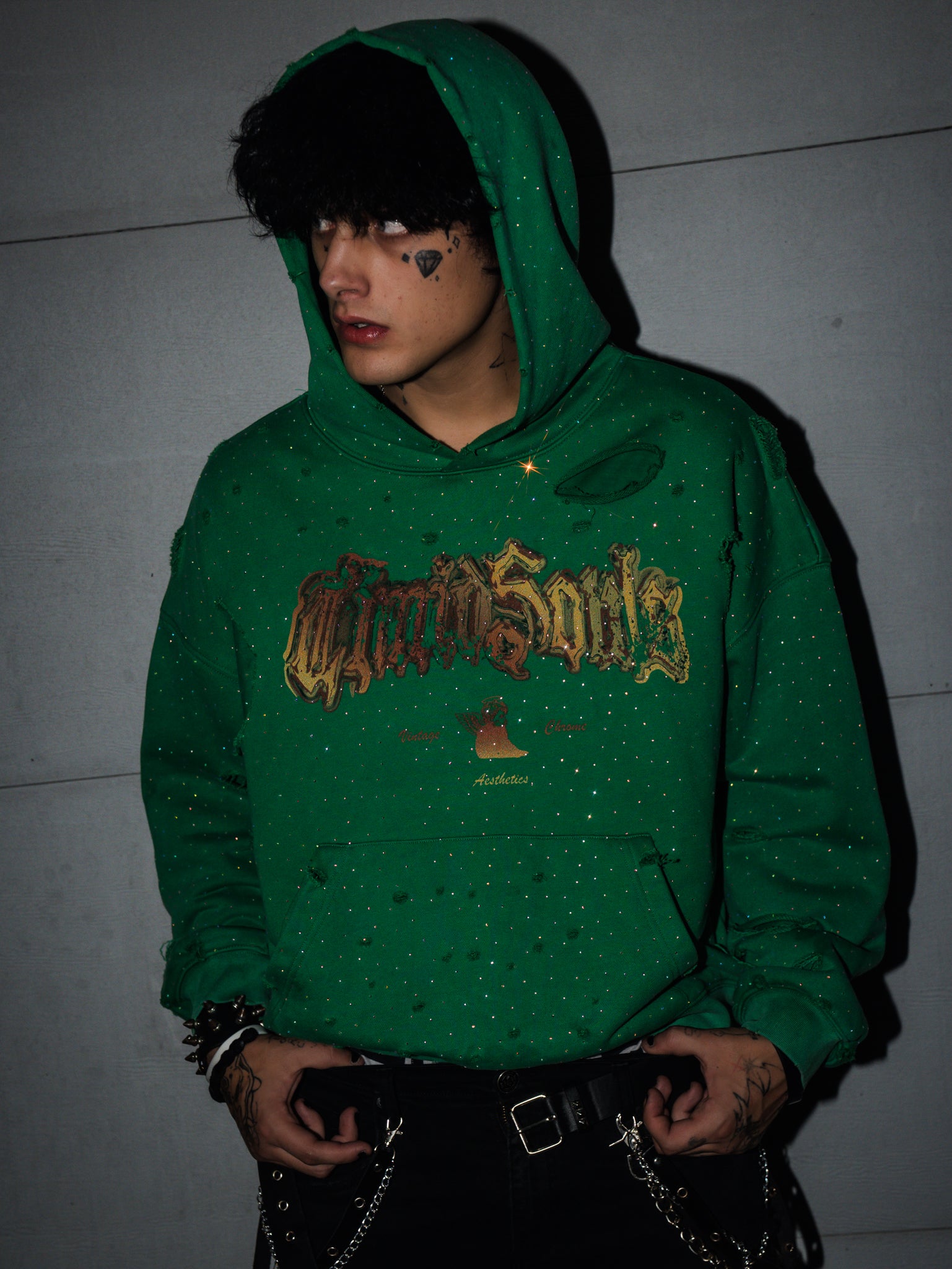 Person wearing a green hoodie with text, standing against a plain background