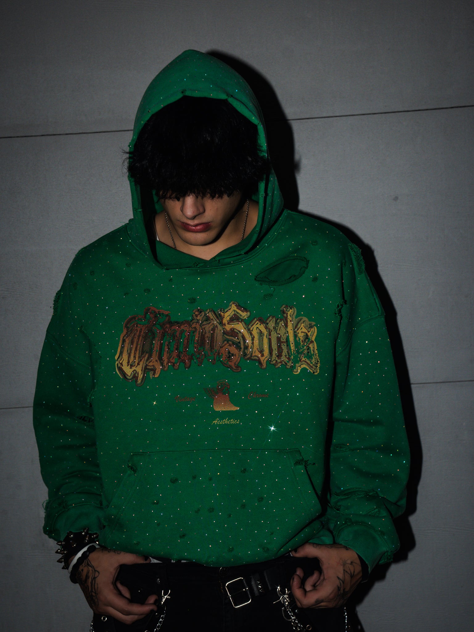 Person wearing a green hoodie with text on it against a plain background
