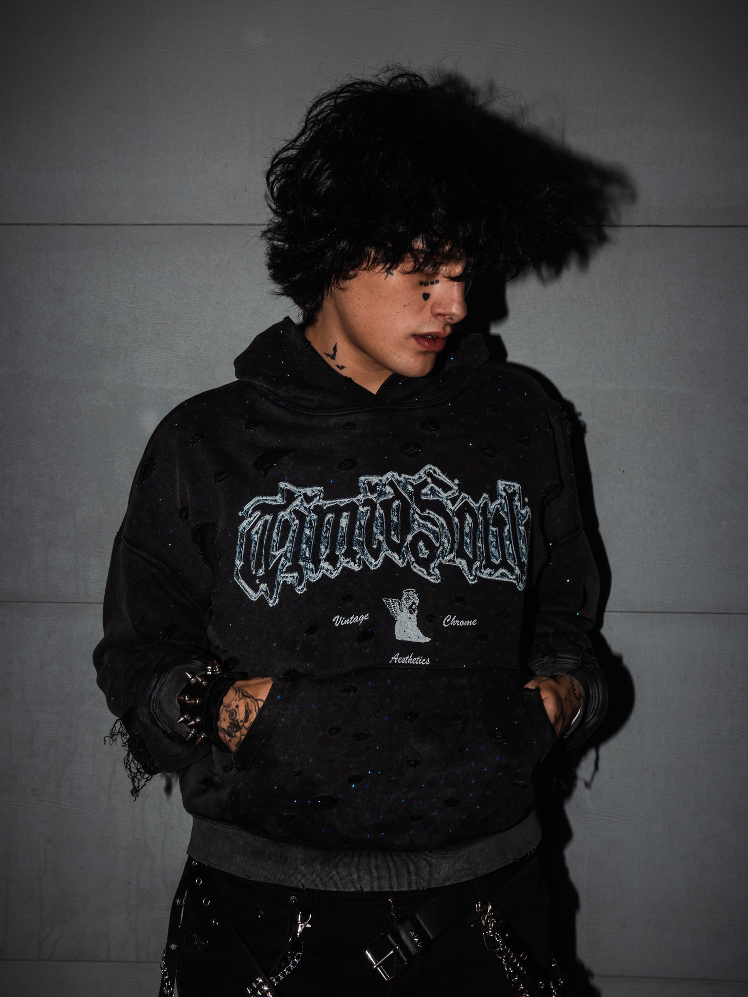 Person wearing a black hoodie with text and graphics against a gray background