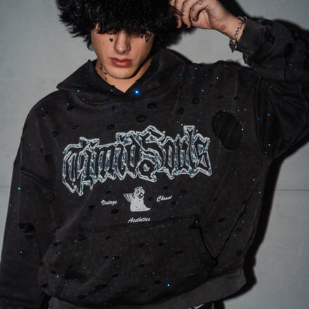 Person wearing a black hoodie with a brand logo against a plain background