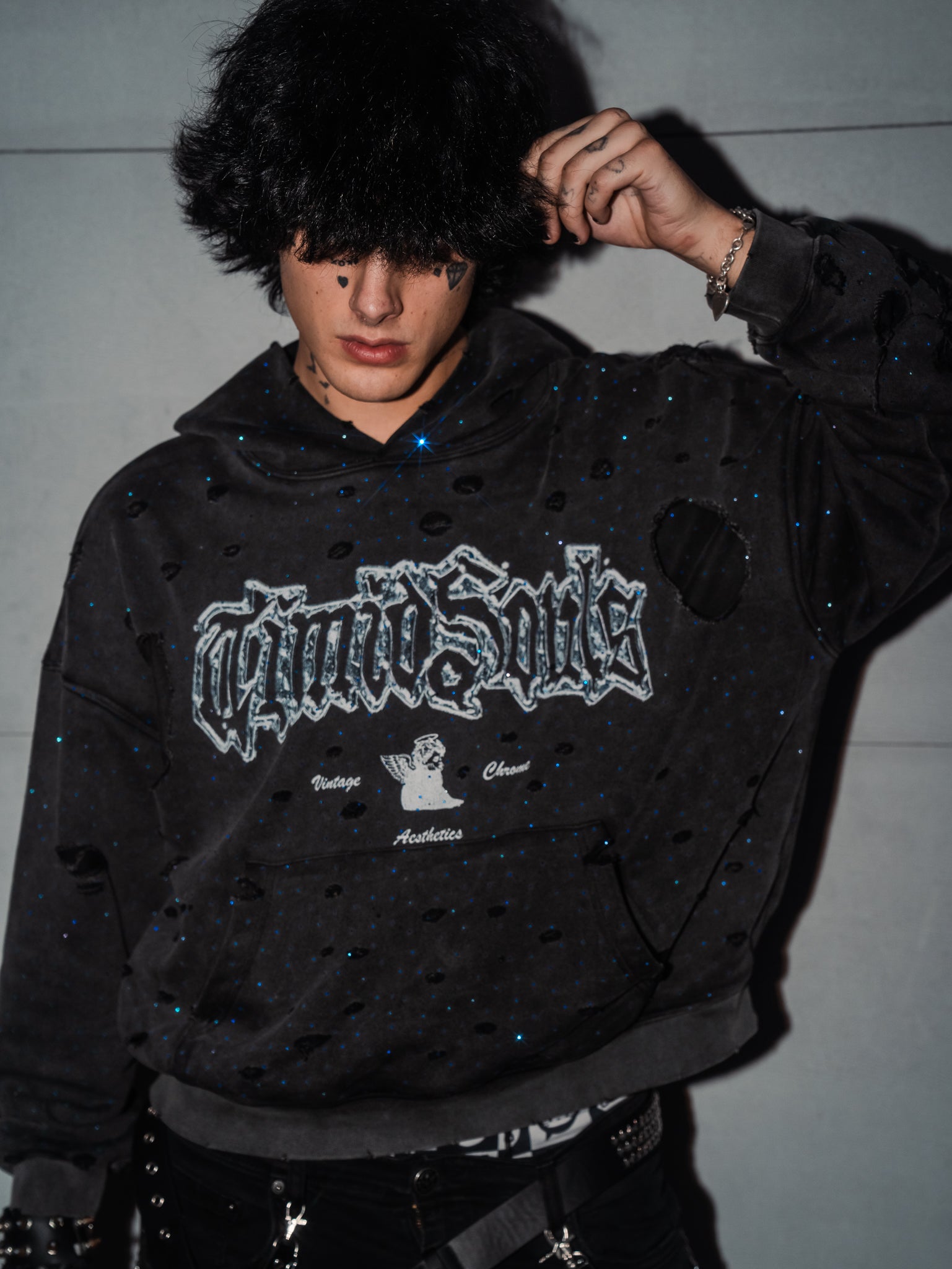 Person wearing a black hoodie with a brand logo against a plain background