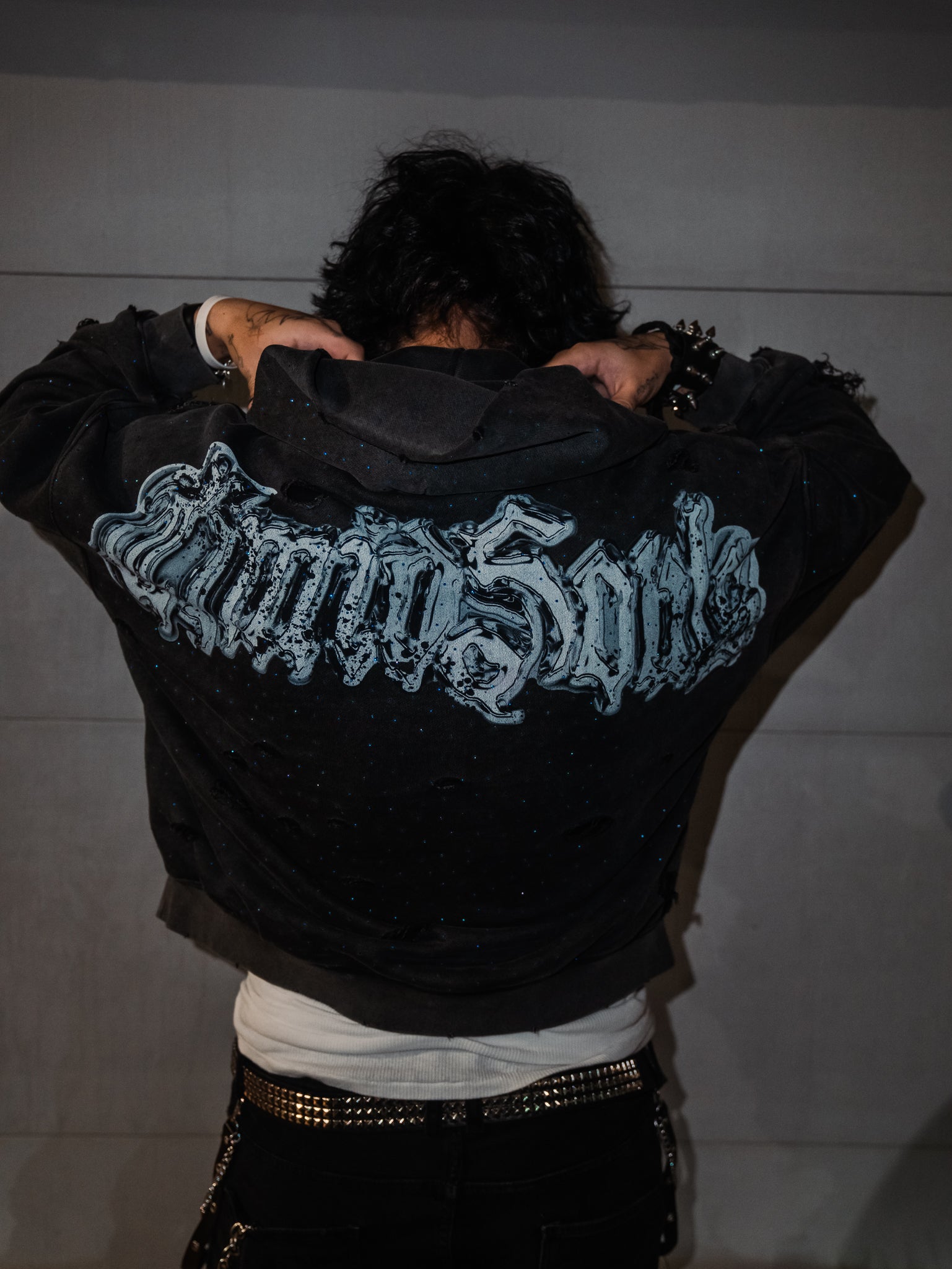 Person wearing a black jacket with text on the back against a plain background