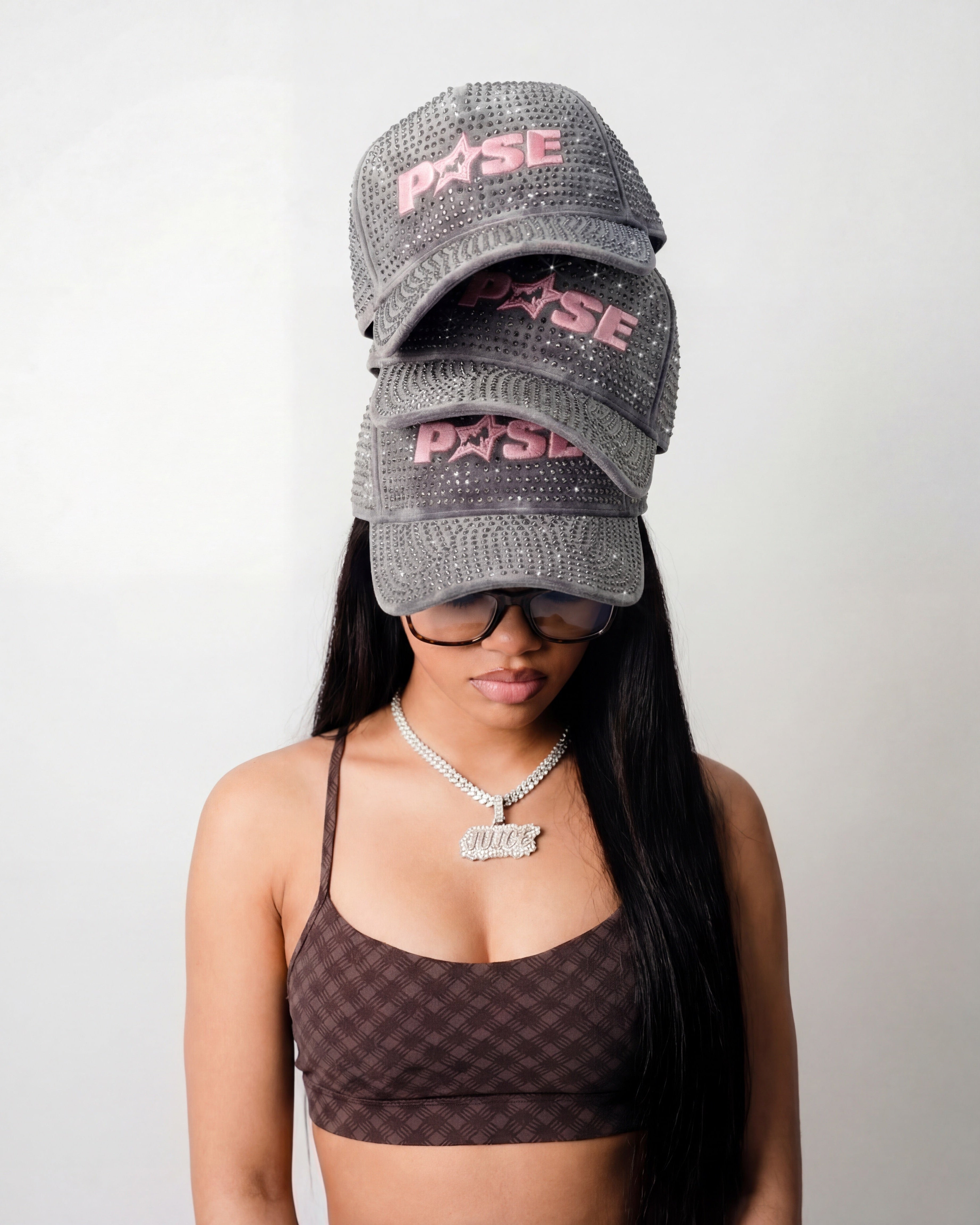 Woman wearing a checkered sports bra and two gray caps with 'P45SE' branding on a plain background