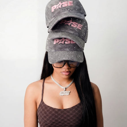Woman wearing a checkered sports bra and two gray caps with 'P45SE' branding on a plain background