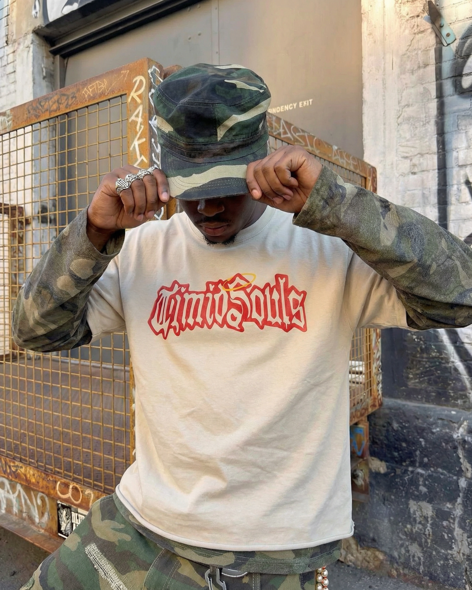 Person wearing a white t-shirt with red text and camouflage clothing in an urban setting