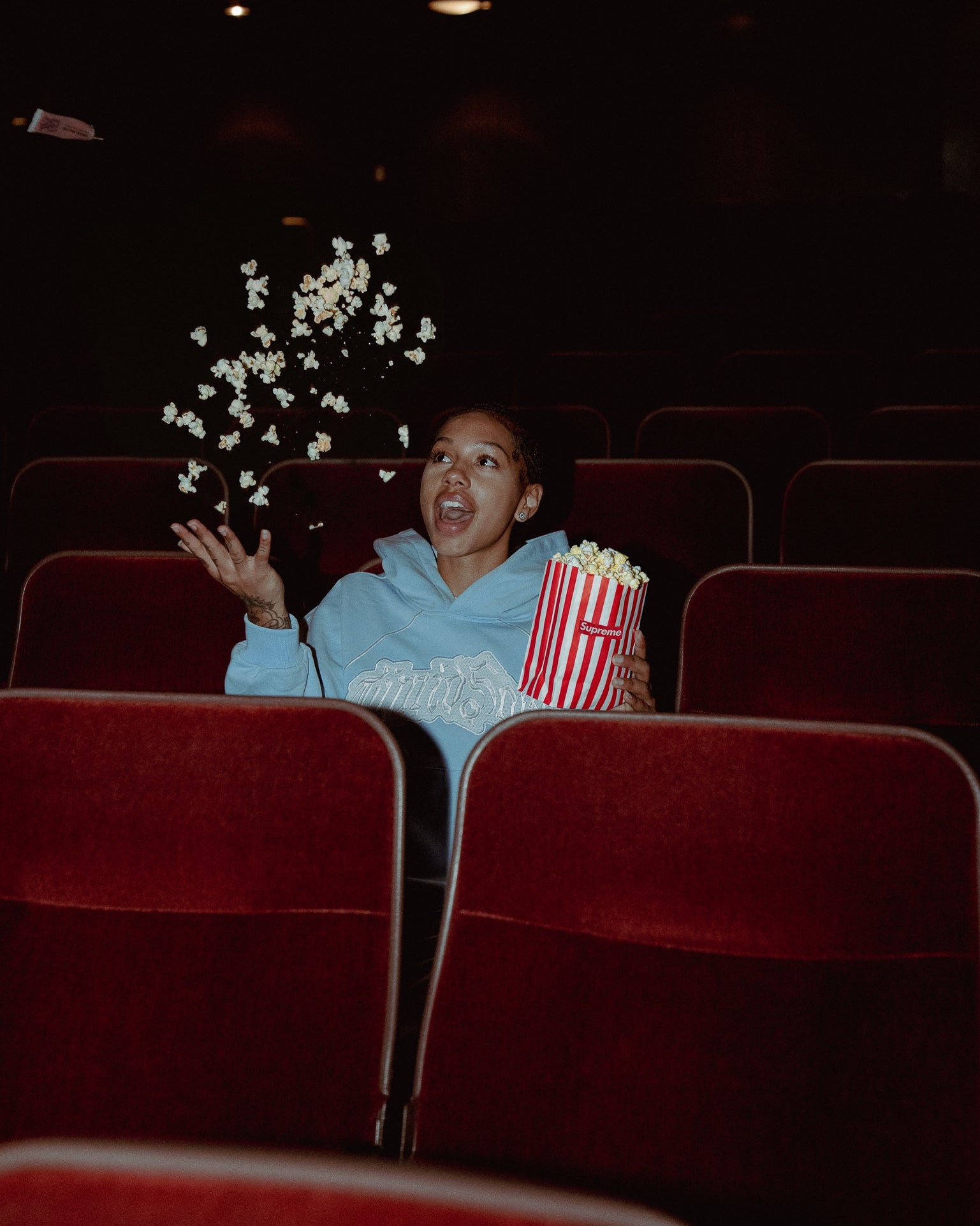 Person in a movie theater with popcorn and a bucket, enjoying a movie.