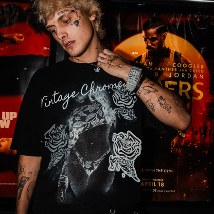 Person wearing a black t-shirt with graphic designs in front of movie theater screens.