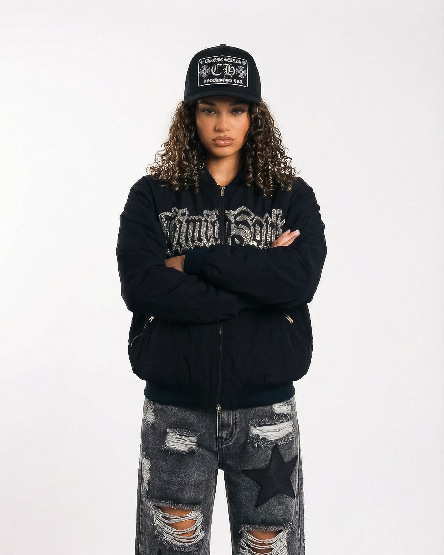 Person wearing a black hoodie with text, black cap, and ripped jeans on a white background