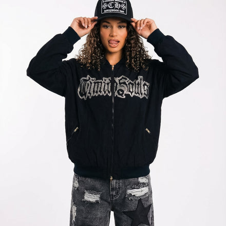 Person wearing a black hoodie with text, black cap, and ripped jeans on a white background