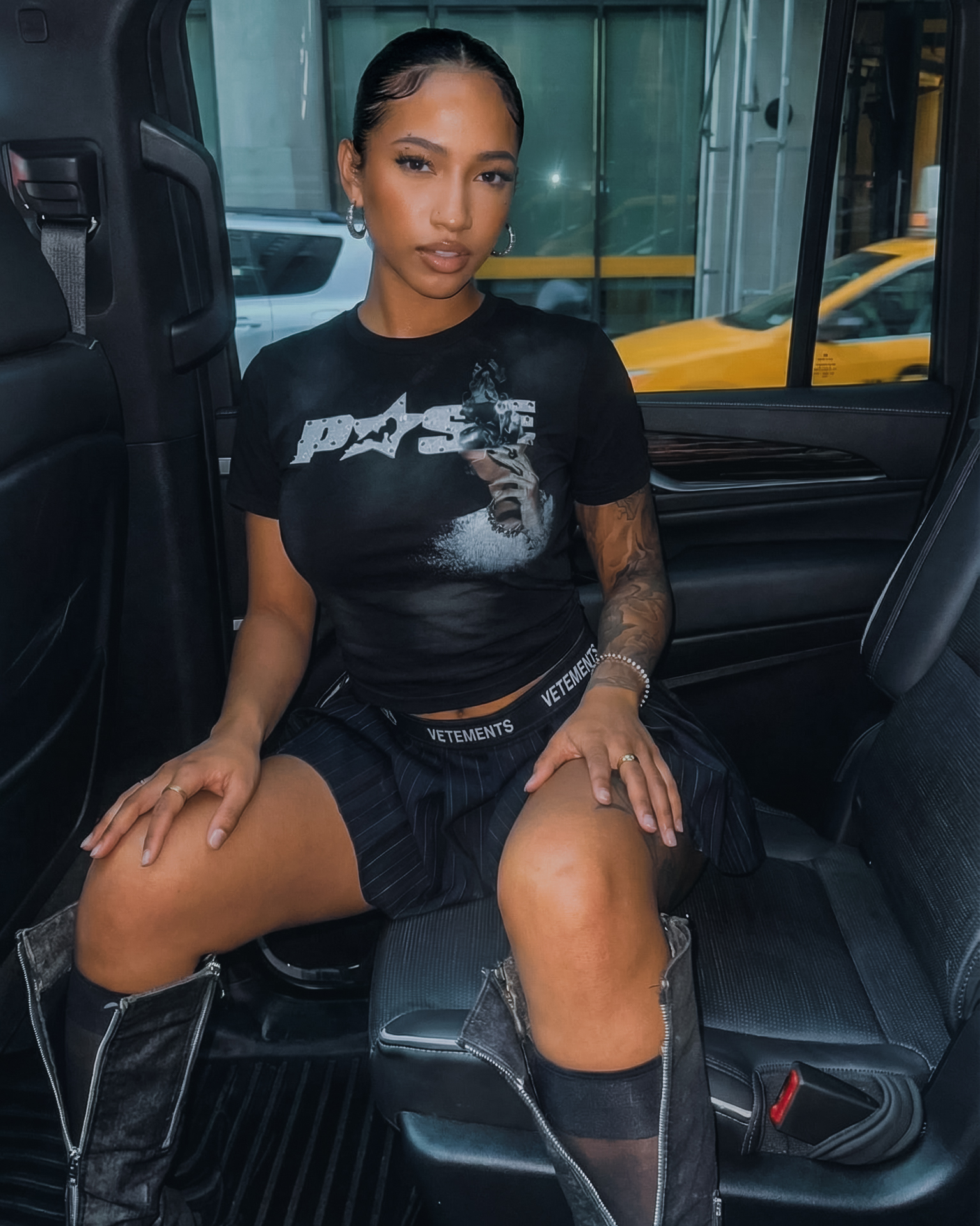 Person sitting inside a vehicle wearing a black t-shirt with a logo.