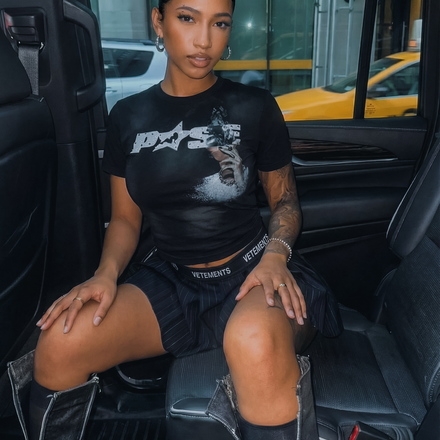 Person sitting inside a vehicle wearing a black t-shirt with a logo.
