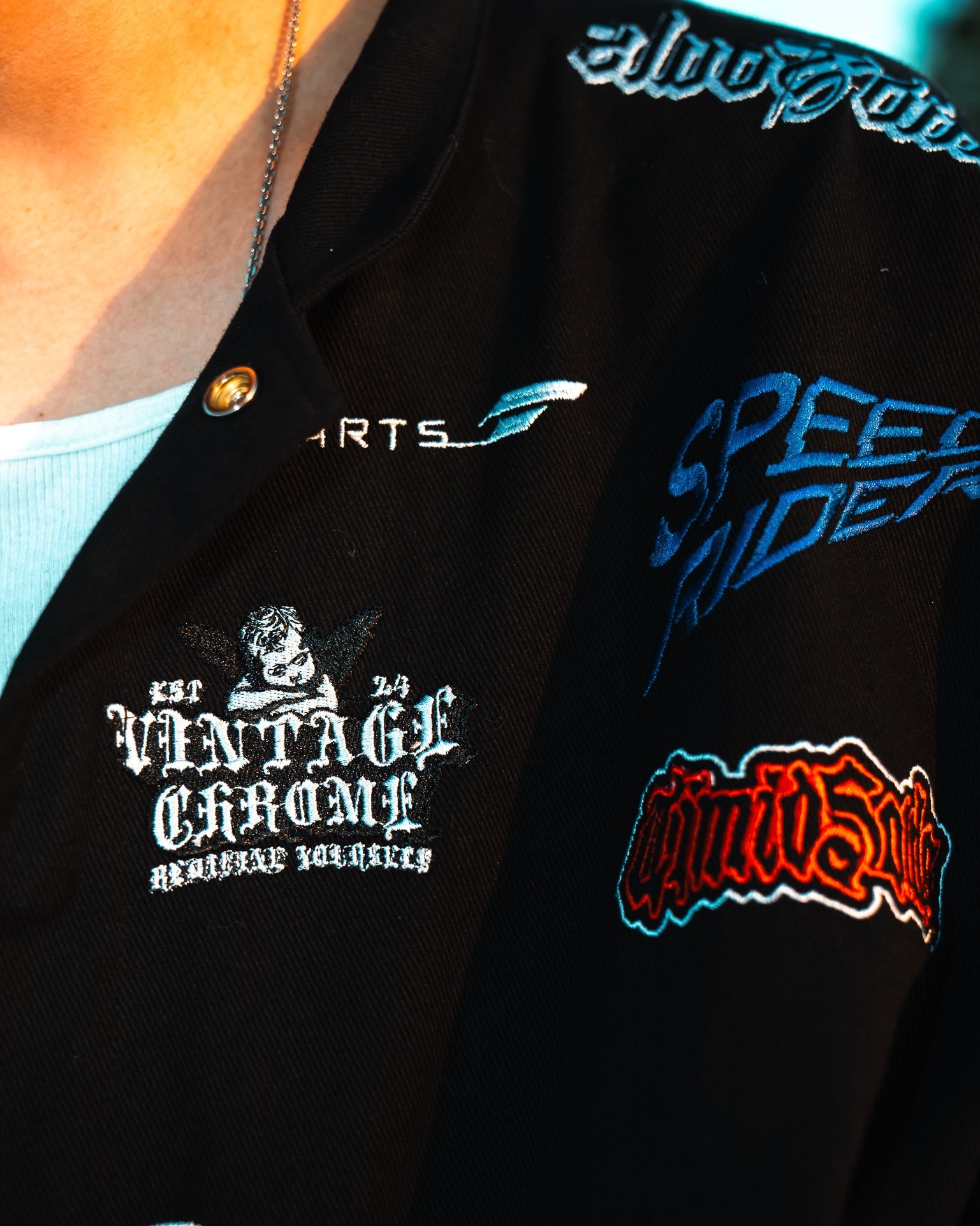 Black jacket with various brand logos on a person wearing it.