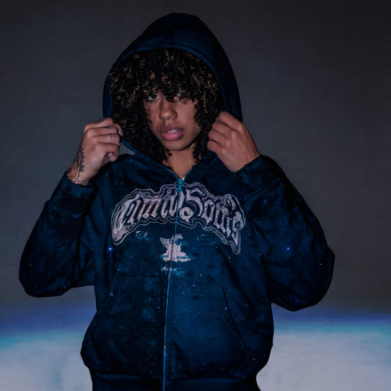 Person wearing a dark blue hoodie with a logo on a dark background