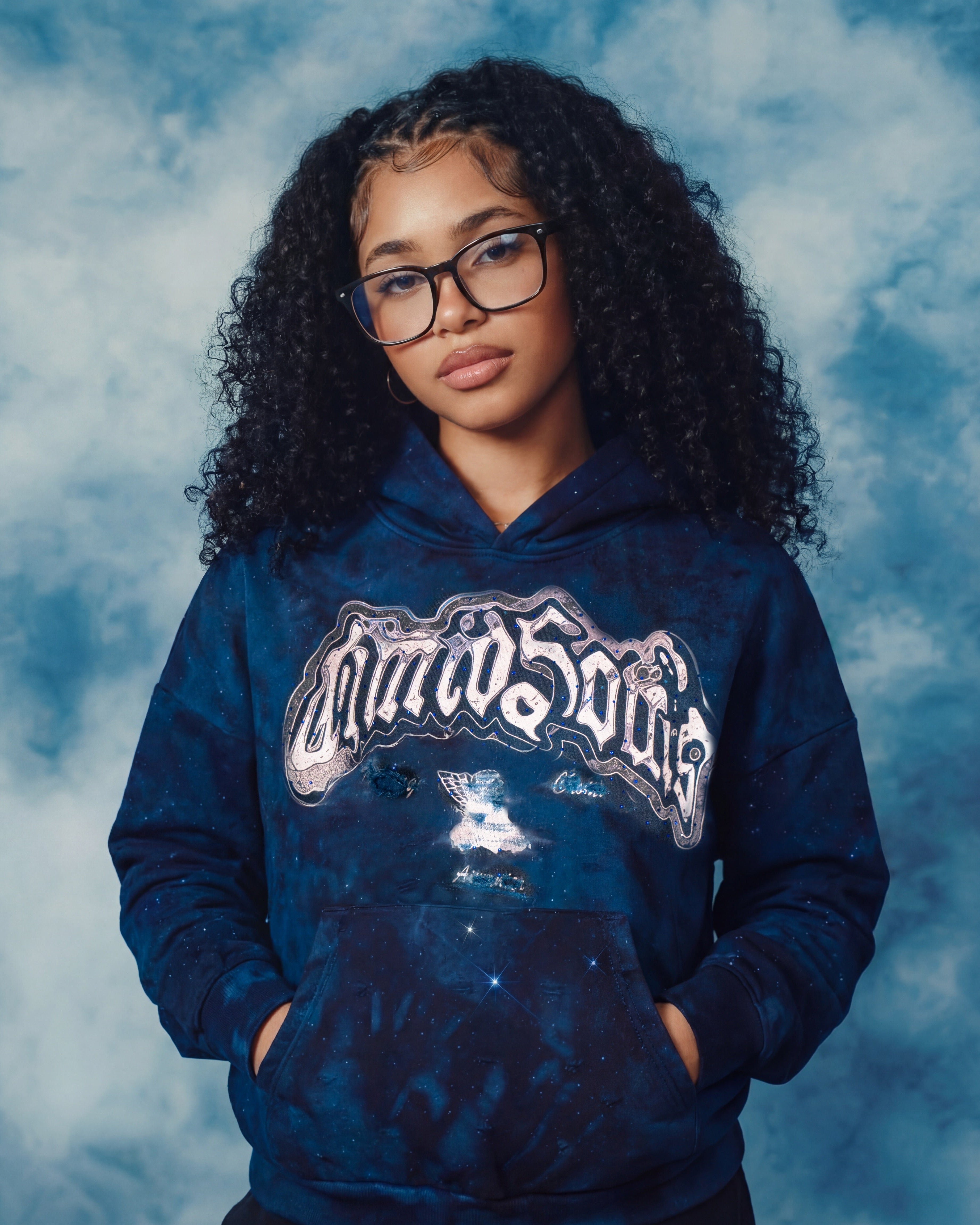 Person wearing a blue hoodie with a logo against a cloudy sky background